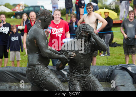 Deux hommes aux prises avec une foule de boue derrière à la Plaine des jeux, Thorney, Somerset, Angleterre Banque D'Images