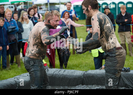 Deux hommes aux prises avec une foule de boue derrière à la Plaine des jeux, Thorney, Somerset, Angleterre Banque D'Images