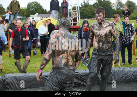 Deux hommes aux prises avec une foule de boue derrière à la Plaine des jeux, Thorney, Somerset, Angleterre Banque D'Images