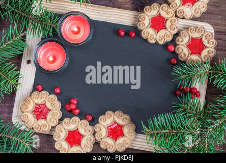 Blank chalkboard entouré de branches de sapin, de deux bougies allumées et quelques cookies avec confiture de petits fruits, haut Vue, télévision lay Banque D'Images