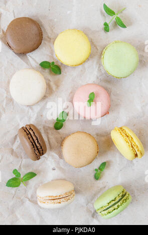 Macarons multicolores et de feuilles de menthe verte sur fond de papier de l'emballage ; haut Vue, télévision lay Banque D'Images