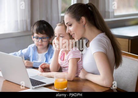 Jeune maman dessins animés sur ordinateur portable avec fille et fils Banque D'Images