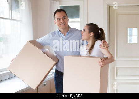 Heureux couple holding boîtes de carton entrant propre maison Banque D'Images