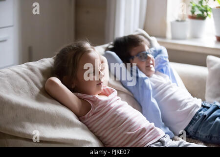 Cute boy and girl lying on cosy sofa relaxing Banque D'Images