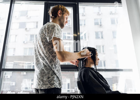 Une femme dans un salon de coiffure en attendant de voir les résultats à la dans un miroir, sourire et parler avec l'artiste Banque D'Images
