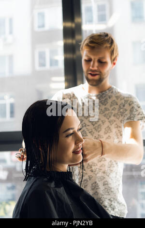 Happy young woman getting une nouvelle coupe de coiffure à parlour Banque D'Images