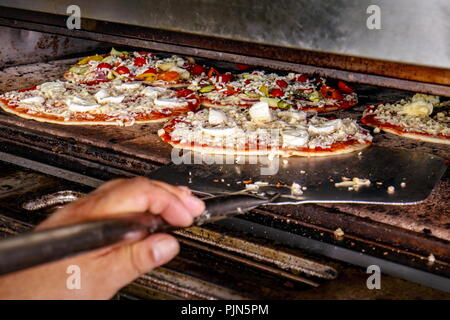 Pizza Chef putting prêt pour la cuisson dans le four électrique Banque D'Images
