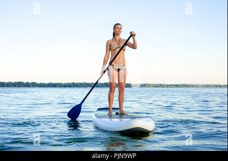 Maillot femme confiante SUP debout avec une pagaie sur la planche de surf Banque D'Images