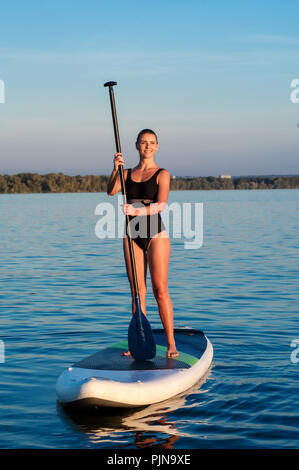 Maillot femme confiante SUP debout avec une pagaie sur la planche de surf Banque D'Images