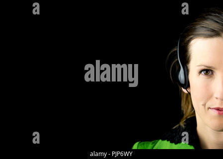Vue partielle de la face d'une jolie femme portant un casque sur un fond sombre avec copyspace conceptual d'un centre d'appels, traducteur, recepti Banque D'Images