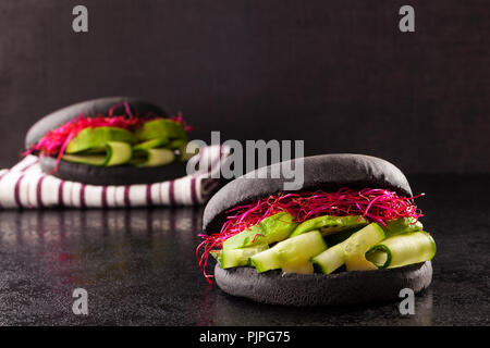 Hamburgers vegan noir sur fond sombre. Banque D'Images