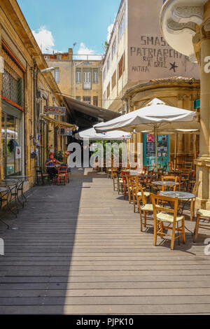 Nicosie, Chypre - 14 mai 2018 : Tables et chaises avec quelqu'un de vous détendre dans de backstreet étroit centre de Nicosie. Banque D'Images