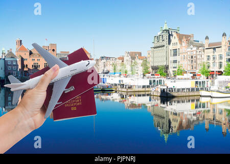 Billet d'avion concept, main tenant passeport rouge avec le plan sur fond d'Amsterdam Banque D'Images