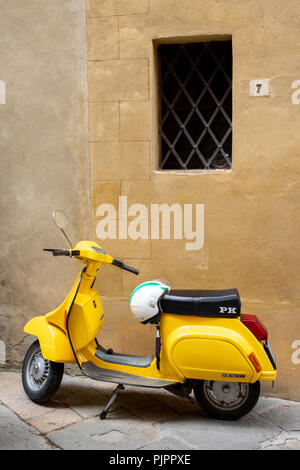 Vespa piaggio jaune, un scooter italien traditionnel avec le casque blanc garé dans une rue de pienza en Toscane Banque D'Images