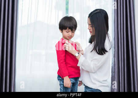 Jeune maman asiatique habillé chemise de préparer son fils aller à l'école. Mère et fils concept. Famille heureuse et Home sweet home thème. Retour à l'éducation préscolaire et Banque D'Images