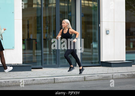 Vue de côté femme sportive courir vite dans l'environnement urbain minimaliste Banque D'Images
