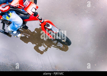 Équitation enfant sur vélo à la flaque. Close-up. Banque D'Images
