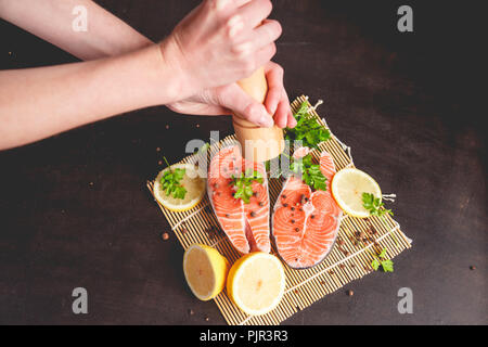 Une femme saupoudre avec du saumon d'un moulin à poivre poivre Banque D'Images