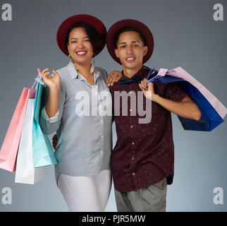 Portrait of young couple with shopping bags isolé sur fond gris Banque D'Images
