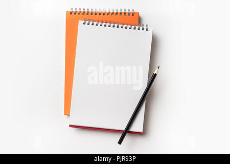 Concept design - Vue de dessus de l'orange et le rouge carnet à spirales et crayon de couleur collection isolé sur fond blanc pour une maquette Banque D'Images