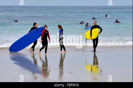 Les jeunes gens portant des planches de surf,Sennen Cove, Cornwall, Angleterre, Royaume-Uni Banque D'Images