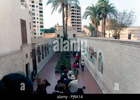 Le Caire, Égypte, 18 février 2017couloir carrelée à l'entrée d'une petite église copte avec une colonne en bois portique du quartier chrétien du Caire avec les gens de l'Ouest et musulmanes vêtements. Banque D'Images