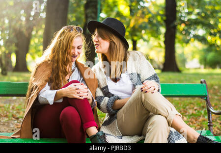 Amis féminins commérages dans le parc sur une journée d'automne Banque D'Images