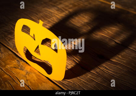 Fond de décor d'Halloween concept. Citrouille Jack O visage effrayé, graphique et ombre lumière dure sur table en bois Banque D'Images