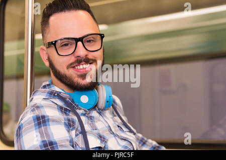 Jeune homme barbu portant des lunettes chemise à carreaux et de prendre les transports en commun dans la ville souterraine. Concept de la navette, de la mobilité, de la vie en ville. Banque D'Images