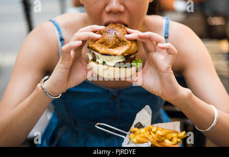 Girl eating burger dans le restaurant close up Banque D'Images