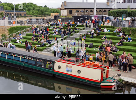 Les personnes bénéficiant de beau temps sur les étapes à la place du grenier à King's Cross, Londres Angleterre Royaume-Uni UK Banque D'Images