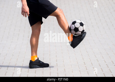Vue latérale du joueur de soccer freestyle ou balle de jonglage avec ses jambes. Banque D'Images