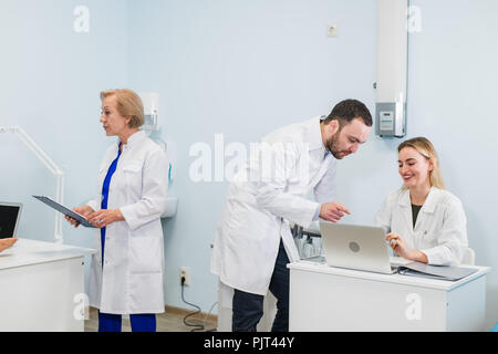 Petit groupe de médecins qui travaillent ensemble dans le cabinet du médecin. Banque D'Images