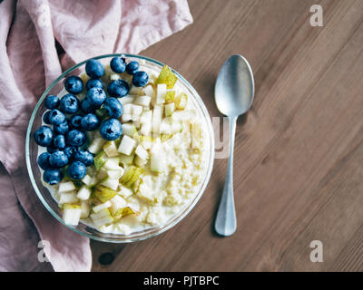 Vue de dessus du bol avec millet bouillie sur fond de table en bois. Porridge de millet bio avec Blueberry et de poire, l'espace de copie pour le texte. Soft focus, sh Banque D'Images