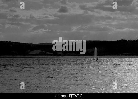 Un surfeur vent prend la dernière course de la journée sur l'estuaire Exe à Exmouth Devon, Angleterre avant que la lumière baisse. Banque D'Images