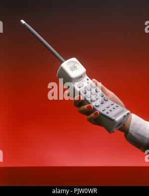 1991 WOMANS HISTORIQUE HAND HOLDING UP TÉLÉPHONE SANS FIL (©Sony CORP 1990) SUR FOND ROUGE Banque D'Images