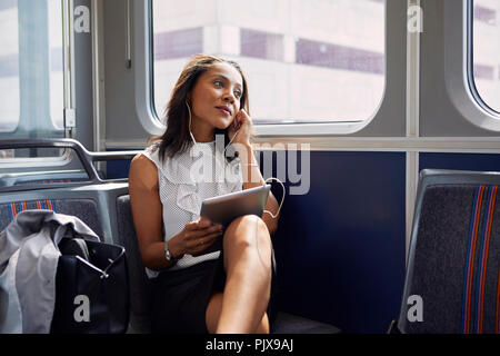 Businesswoman using digital tablet on train Banque D'Images