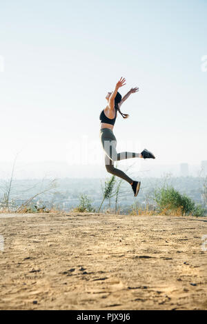 Femme sautant dans l'air sur la colline Banque D'Images