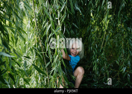 Garçon jouant sous willow tree Banque D'Images