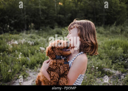 Girl laughing at puppy's kisses Banque D'Images