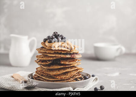 Vegan pile de pancakes aux myrtilles avec du beurre d'arachides et le sirop. Concept de l'alimentation propre. Banque D'Images