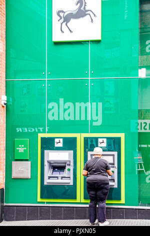 Dame à l'aide d'un distributeur automatique de la banque Lloyds, Bristol, England, UK Banque D'Images