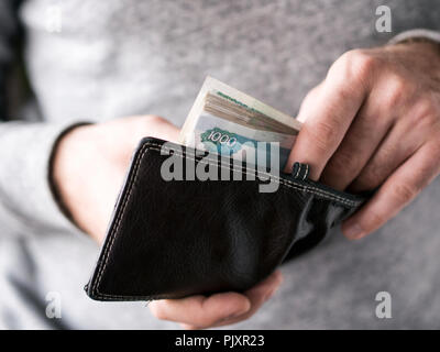 Sortir les mains de roubles russes wallet. Gros plan sur les mains d'un homme comme il est en train d'un billet de son portefeuille Banque D'Images