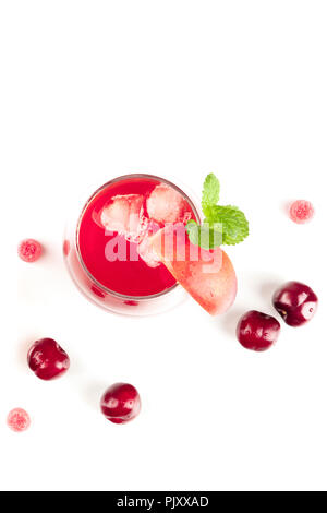 Photo prise à la verticale d'un rouge vibrant verre de cerises et des bonbons sur blanc Banque D'Images