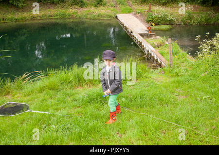 Garçon de quatre ans à Meon Springs Trout pêcherie, East Meon, Hampshire, Angleterre, Royaume-Uni. Banque D'Images