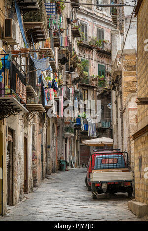 Une scène de rue de Palerme avec lave-pendaison depuis les balcons des appartements résidentiels et un traditionnel à trois roues Piaggio Ape van stationné outsid Banque D'Images