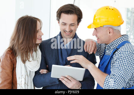 Travailleur et couple using tablet pc at construction site Banque D'Images