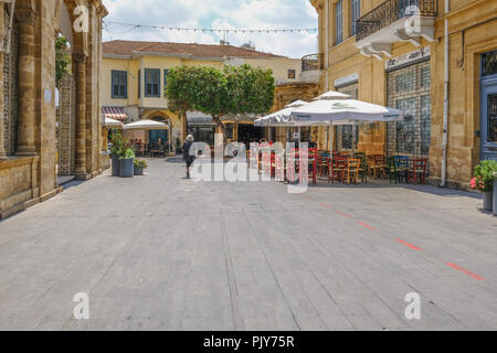 Nicosie, Chypre - 14 mai 2018 : vue arrière de dame de marcher à travers l'avant de l'église Sainte Marie dans le centre de Nicosie. Les tables avec chaises peuvent été se Banque D'Images