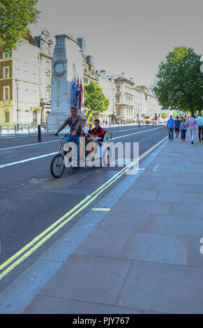 Whitehall, Londres, UK - 8 juin 2018 : Pedicab avec chauffeur et deux jeunes passagers voyageant le long de Whitehall et juste de passage le cénotaphe. Banque D'Images