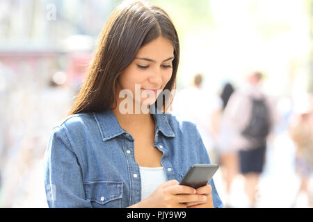 Adolescent utilise un téléphone intelligent debout dans la rue Banque D'Images